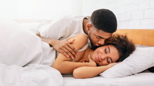 Handsome man kissing woman on cheek under in bed