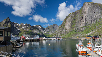 Sommer auf den Lofoten, Spiegelung der Berge im Reinefjord, bunte Boote liegen im kleinen Hafen - obrazy, fototapety, plakaty
