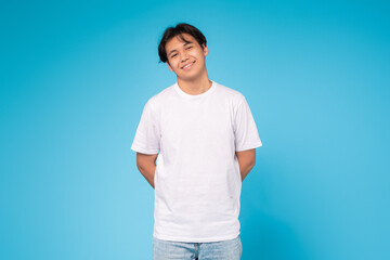 Smiling young guy standing casually, blue background