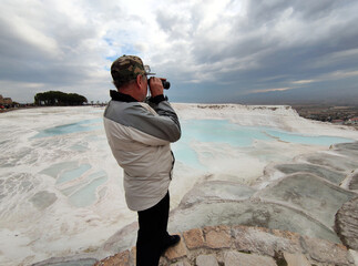 A man looking through a spotting scope from above at the panorama of Pamukkale, Turkey