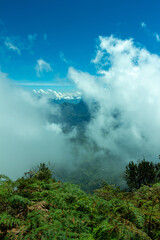 Bright panorama of the cloudy Andes Mountains from the Cerro las Nubes, Mount of the Clouds, in Jerico, Jericó, Antioquia, Colombia. Blue sky whith clouds and mist. Green lush vegetation. Ferns.
