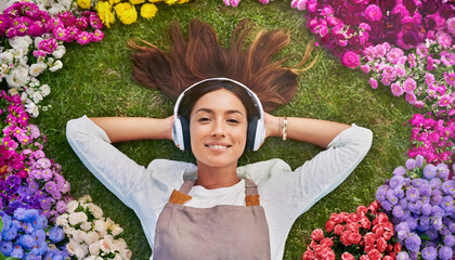 Ragazza felice ascolta musica rilassante distesa in mezzo ad un campo di fiori. - obrazy, fototapety, plakaty