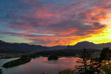 Panoramic sunset view on Lake Faak from Taborhoehe in Carinthia, Austria, Europe. Surrounded by high Austrian Alps mountains. Water surface reflecting soft sunlight. Remote alpine landscape in summer