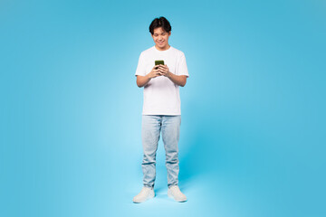 Fototapeta na wymiar Young guy using smartphone with focus, blue background