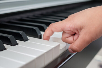 Closeup to a child hand using his one finger to press the piano key