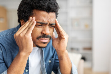 Stressed Black Man Experiencing Severe Headache At Home