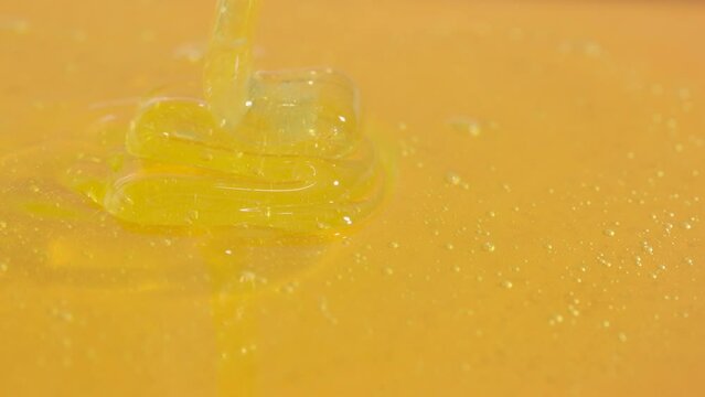 Healthy organic honey. Sweet fresh golden honey pouring on the yellow glass background, thick honey dripping from above.