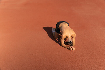 Athlete lying on the ground, crestfallen and sweaty, on an orange sports field. Large copy space on the left. Concept of disappointment and effort in sport