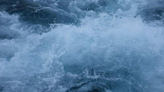 Close-up of the seething water in the sea behind the ship. A splash of sea waves behind a large boat at sea. 