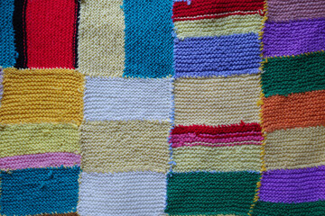 Colorfull knitted patchwork blanket stitched together.