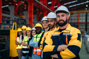 Portrait of industrial worker inspecting and check up machine at factory machines. Background is technician team.