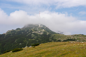 Hiking trail leading to mountain peak Dobratsch, Villacher Alps, Carinthia, Austria, Europe. Alpine meadow along the way to the radio tower on top. Panoramic view of hills and mountains. Wanderlust - obrazy, fototapety, plakaty