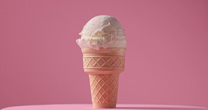 close-up of decorative sugar sprinkles falling on rotating ice cream ball on a pink background, slow motion video