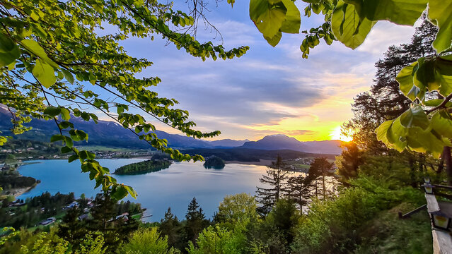 Panoramic sunset view on Lake Faak from Taborhoehe in Carinthia, Austria, Europe. Surrounded by high Austrian Alps mountains. Water surface reflecting soft sunlight. Remote alpine landscape in summer