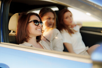 Three friends sharing a moment of joy while on a road trip as the sun sets, capturing the essence of friendship and adventure.