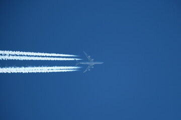 Airplane in the blue sky with contrails. - obrazy, fototapety, plakaty