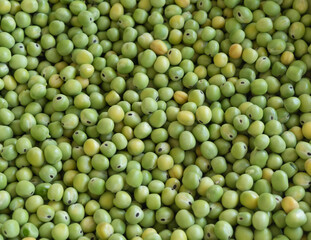 A bunch of green peas are spread out in a pile