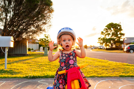 Toddler on trike with open mouthed shock expression wearing helmet