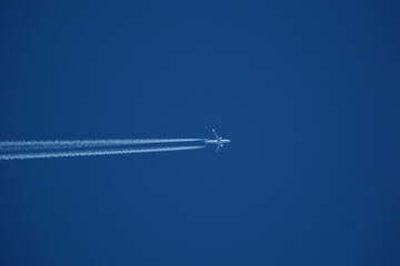 Airplane in the blue sky with contrails.