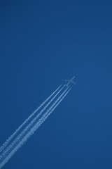 Airplane in the blue sky with contrails.
