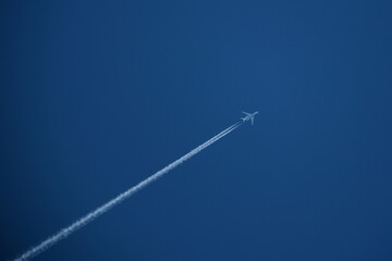 Airplane in the blue sky with contrails.