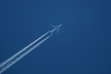 Airplane in the blue sky with contrails.