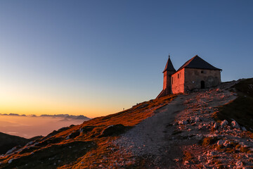 Scenic sunrise view of chapel Maria am Stein on top of mountain peak Dobratsch, Villacher Alps,...