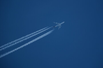 Airplane in the blue sky with contrails.