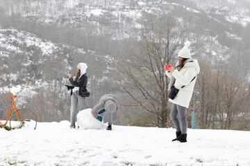 Three people are captured in a casual and candid manner as they enjoy a snowy day outside, each...
