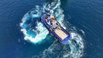 Aerial drone top down photo of industrial tug assisting boat cruising in deep blue Mediterranean sea - obrazy, fototapety, plakaty