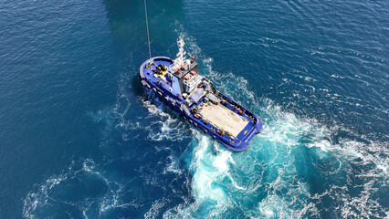 Aerial drone top down photo of industrial tug assisting boat cruising in deep blue Mediterranean sea - obrazy, fototapety, plakaty
