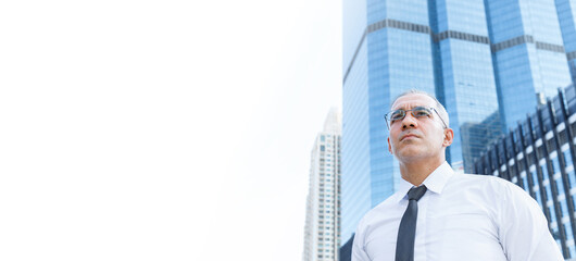 Portrait of mid adult cheerful CEO businessman entrepreneur professional standing at business aria in the city with building and sky background. - obrazy, fototapety, plakaty