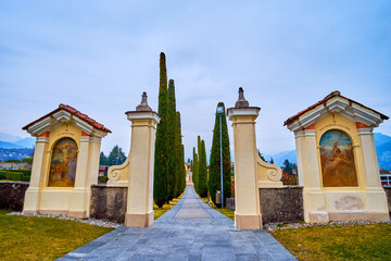 The main entrance and the alley with cypress trees of Sant'Abbondio Chuch, Collina d'Oro, Switzerland