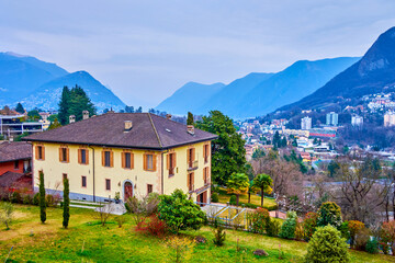 Old residential house and Alpine mountains on background, Collina d'Oro, Switzerland