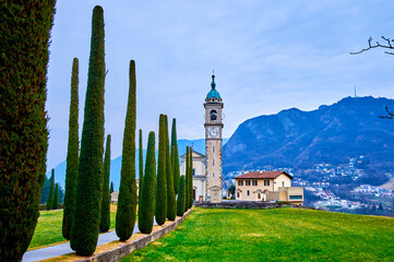 The scenic alley with cypress trees leads to Sant'Abbondio Chuch, Collina d'Oro, Switzerland - obrazy, fototapety, plakaty