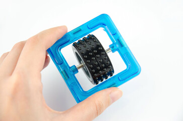Blue transparent magnet square with black wheel inside (constructor for kids), closeup in a hand on...