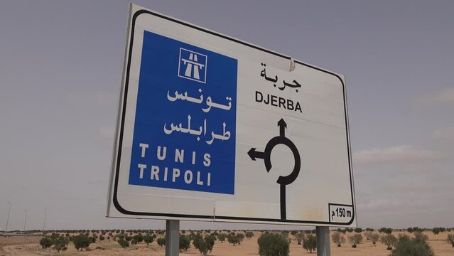 Traffic sign in Tunisia with direction to Tunis, Tripoli (the capital city of Libya), and Djerba island. International travel and infrastructure North Africa.
