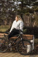 Naklejka na ściany i meble Woman Sitting on Bench Next to Bicycle