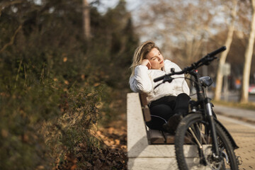 Woman Enjoying Sunny Day on Park Bench Next to Bike