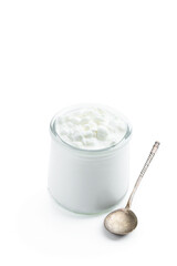 Granular cottage cheese with cream in a glass jar isolated on white
