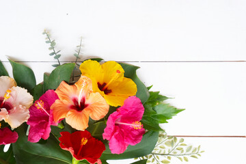 Tropical flowers and leaves on wooden background with copy space, summer vacational background