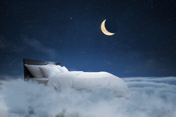 Fototapeta premium Bed with pillows and a blanket flies in the clouds with a night starry sky with the moon, creative idea. Sweet dream, concept. Night rest