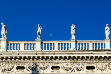 Scenic view of monumental balustrade with statues of Saint Mark Library in Venice, Veneto, Northern Italy, Europe. Designed renaissance architect Sansovino. Day moon and clear blue sky - obrazy, fototapety, plakaty