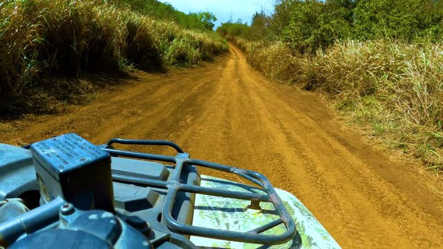 Pov footage of riding a quad cycle on an orange road in the mountains. Driver’s pov of an ATV tour in West Maui mountains, Hawaii.
