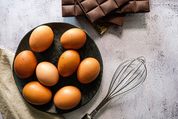 Vista superior de ingredientes frescos para fazer bolo de chocolate. Ovos sobre prato e barra de...