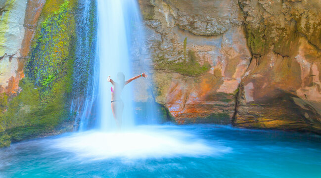 A beautiful woman wearing a bikini bathes in a waterfall - Natural pools with blue water in a rocky Sapadere waterfall and canyon - Alanya, Turkey
