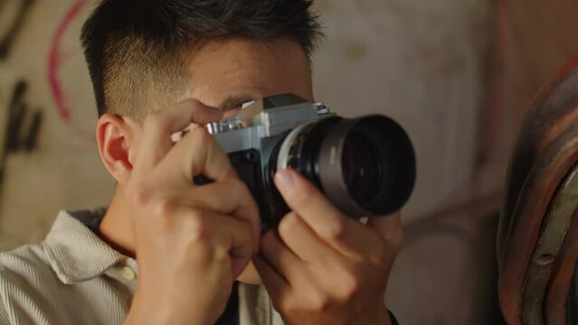 Close up of excited Asian man taking pictures inside abandoned house on camera