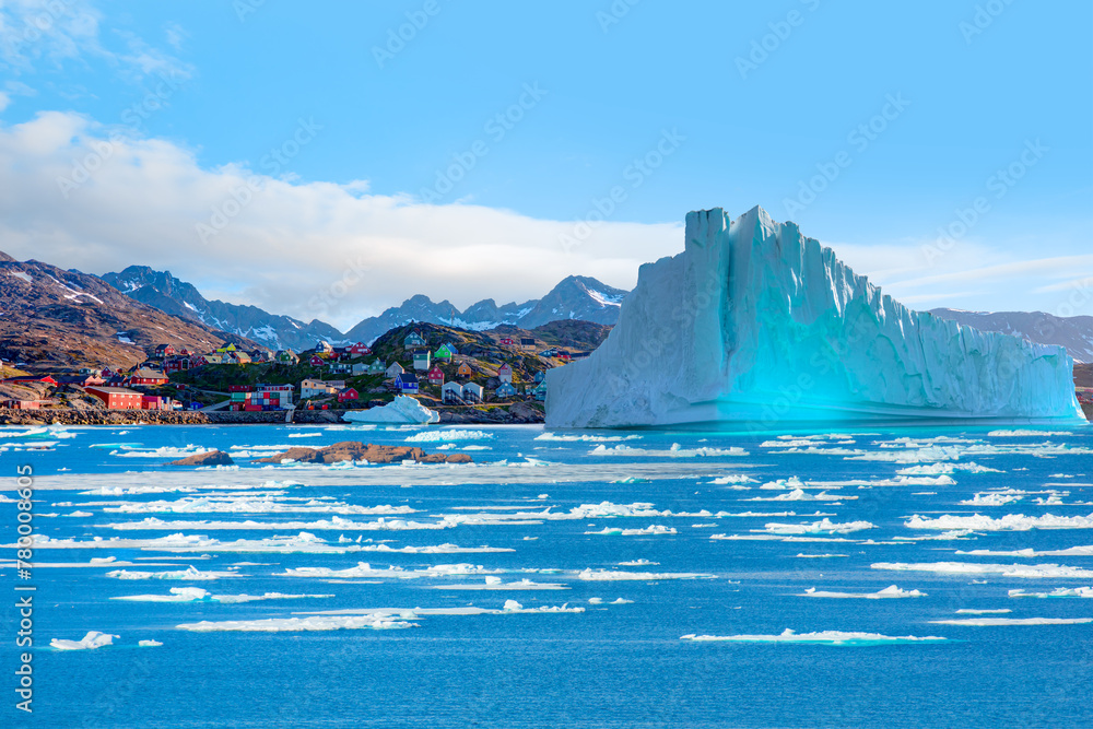 Wall mural melting of a iceberg and pouring water into the sea by the coast of greenland - picturesque village 