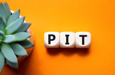 PIT - Personal Income Tax symbol. Wooden cubes with words PIT. Beautiful orange background with...