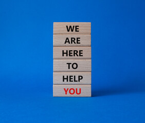 We are here to help you symbol. Concept words we are here to help you on wooden blocks. Beautiful blue background. Business and we are here to help you concept. Copy space.